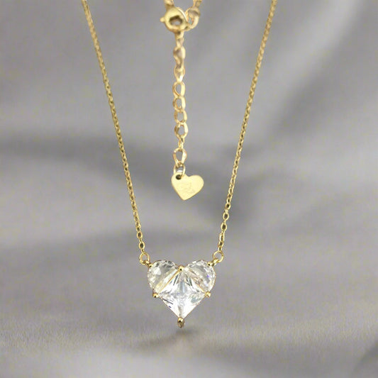 A gold-colored zircon heart necklace with a chain.