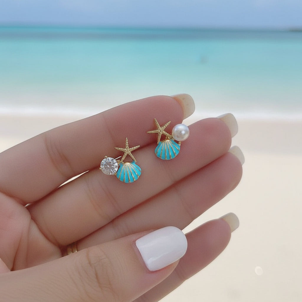Aqua Shell Pearl & Crystal Starfish Earrings on a hand against a beach background