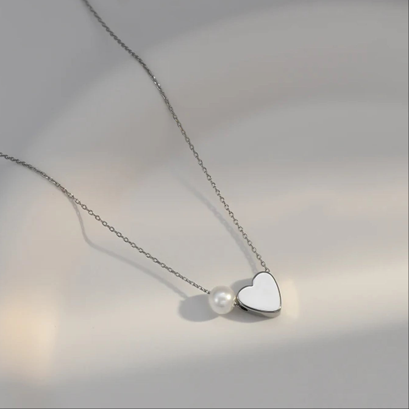 Silver Pearl Heart Necklace with a heart-shaped pendant and pearl on a neutral background