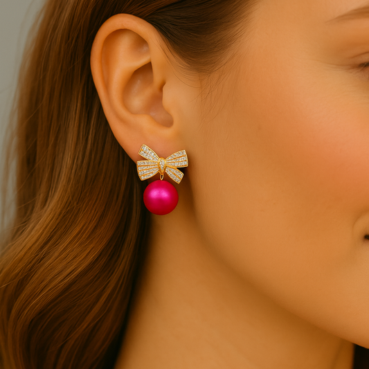 Close-up of a woman wearing a Pink Ornament Bow Earring with a pink bead.