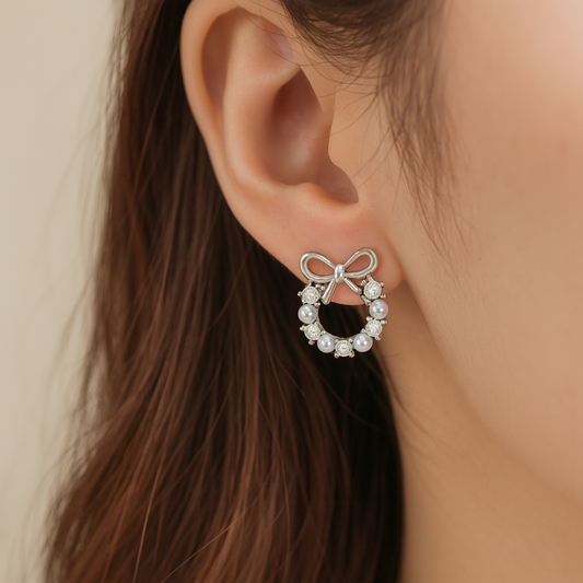 Silver Bow Wreath Earrings with pearls worn by a person with brown hair.