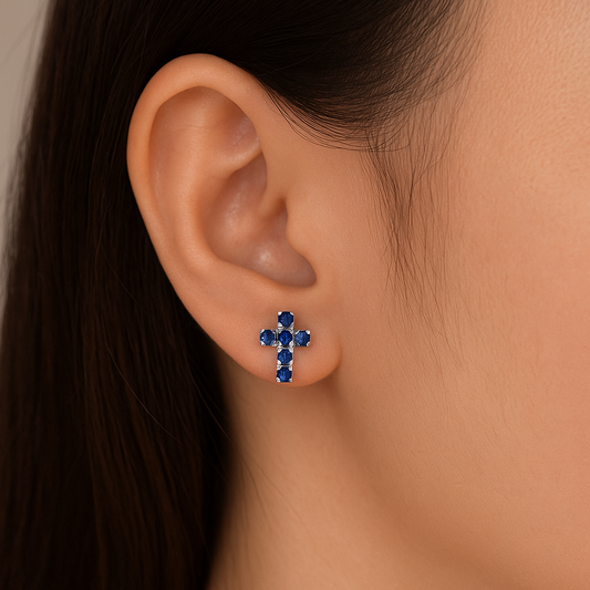 Close-up of an ear wearing a Silver Mini Blue Crystal Cross Earring.