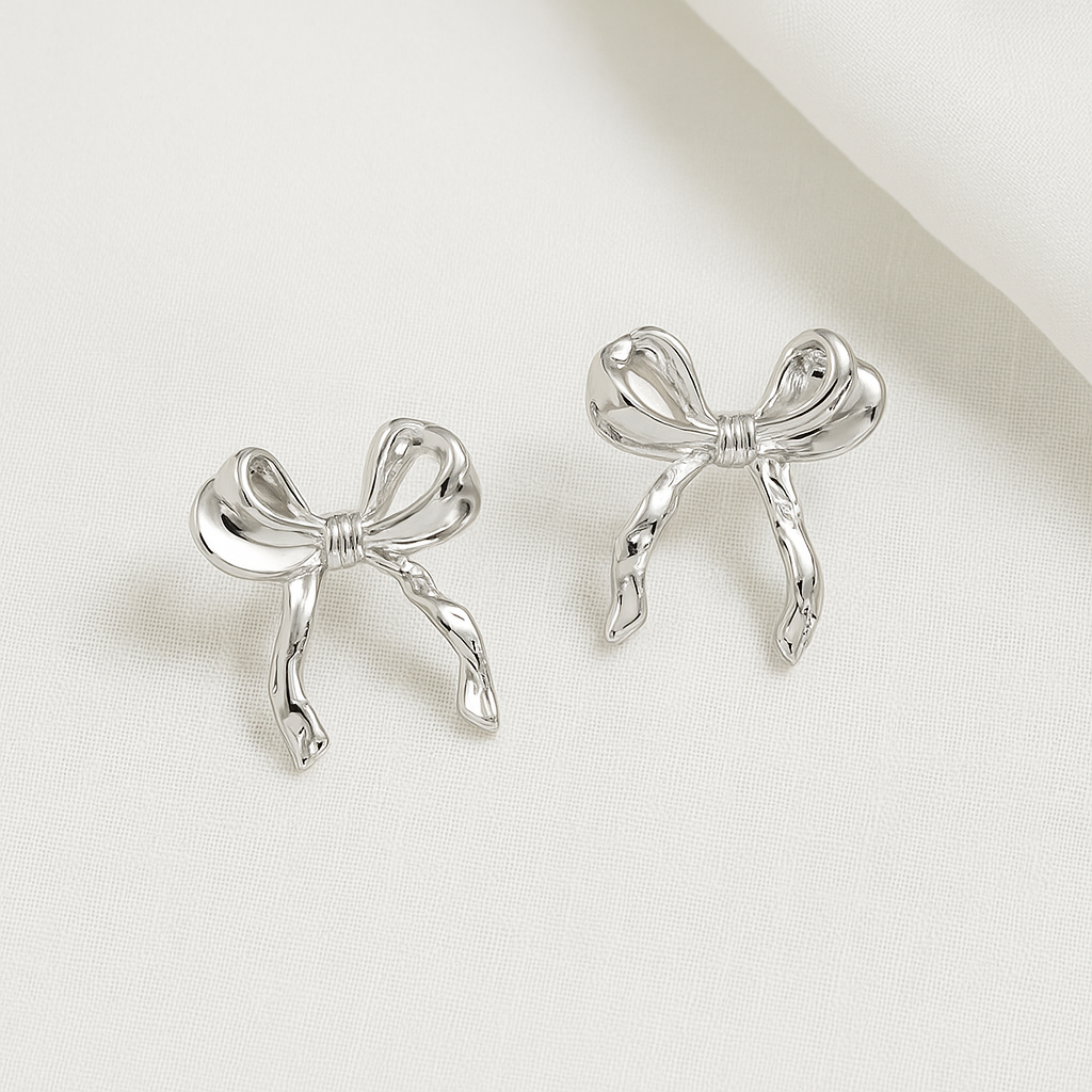 Silver Bow Ribbon Earrings on a light beige background