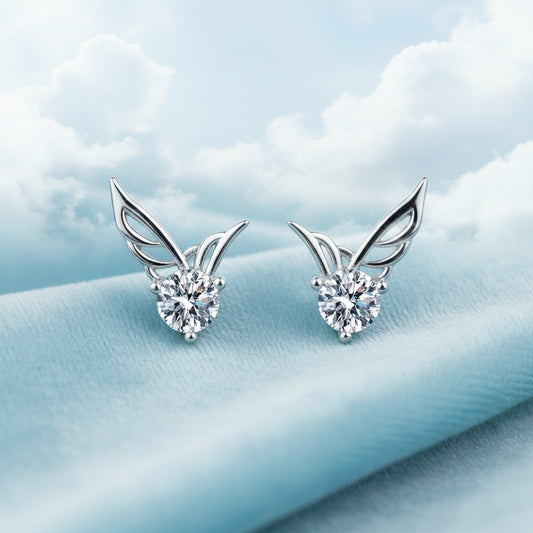 Silver Crystal Angel Wing Stud Earrings with diamond-like stones on a blue textured background