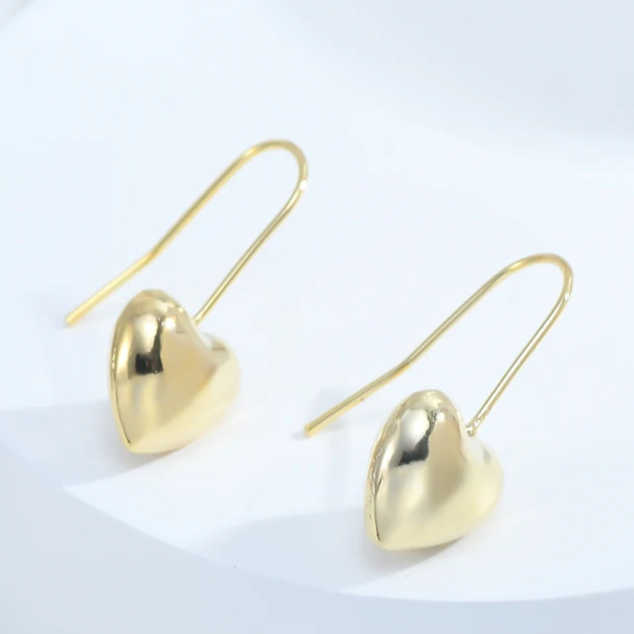 Gold Heart Drop Earrings laying on white background