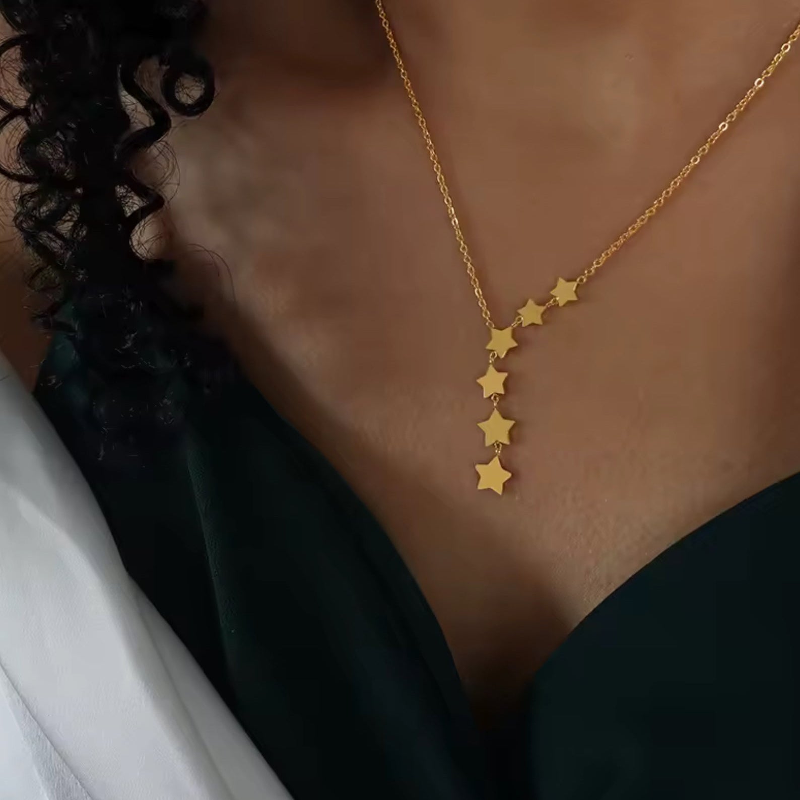 Gold star necklace on a person's neck against a neutral background