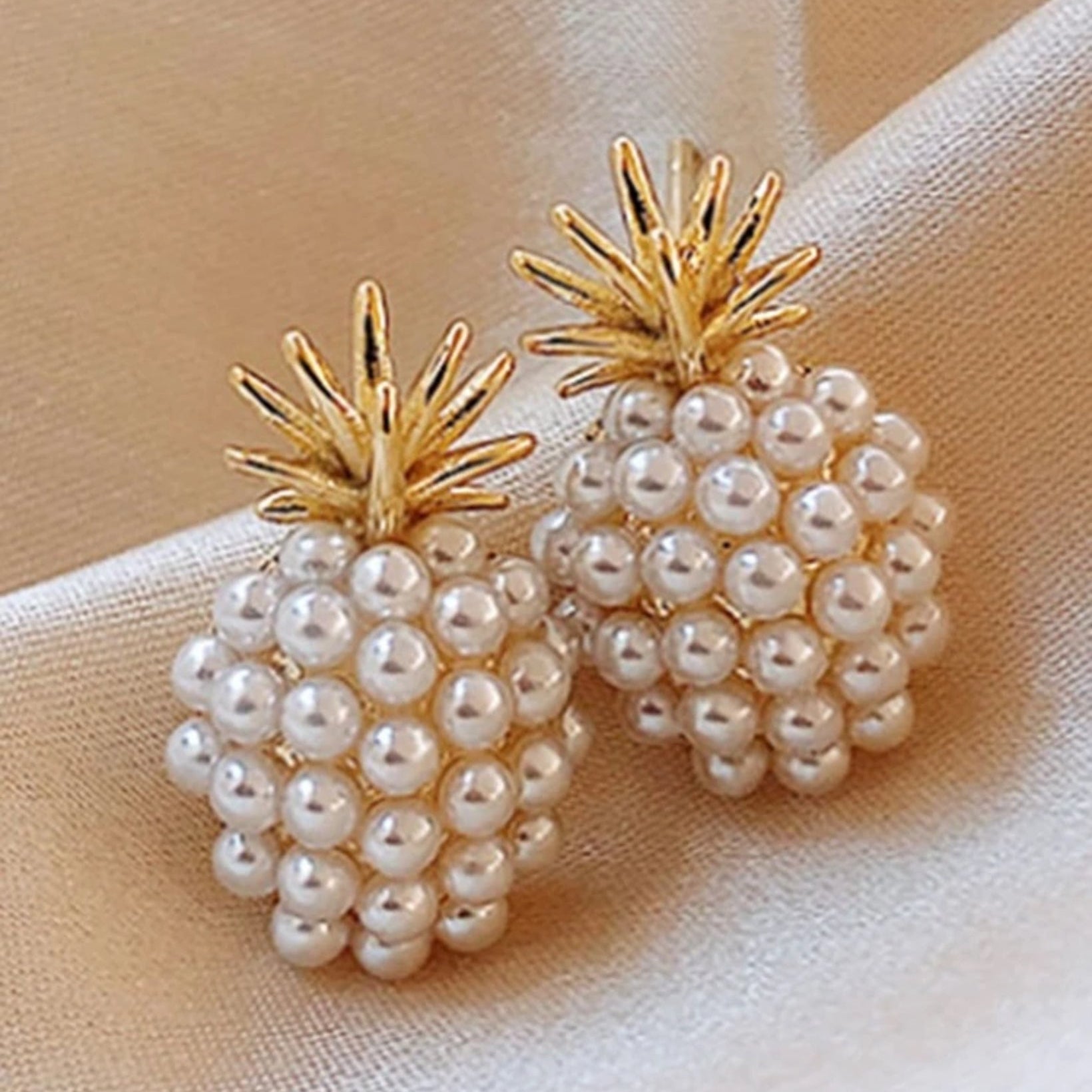 A pair of gold-tone pineapple-shaped earrings adorned with white imitation pearls.