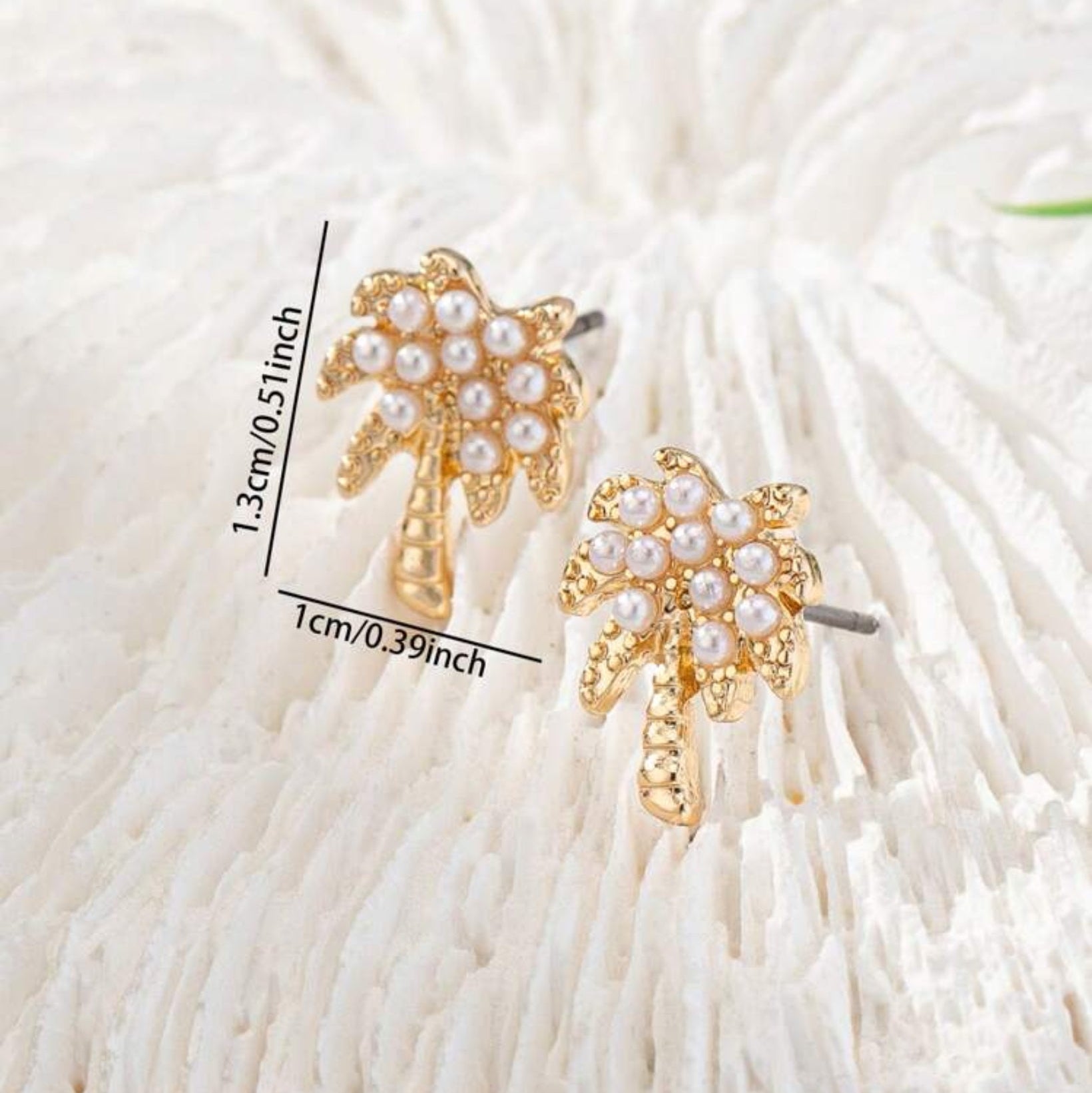 Gold Palm tree-shaped earrings with pearl details on a white background
