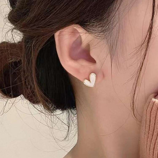 White heart earrings worn by a woman with a neutral background