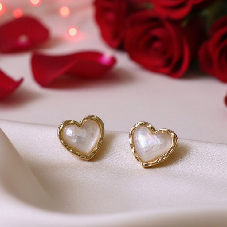 Gold & White Opalescent Heart Earrings with gold frames on a beige fabric background