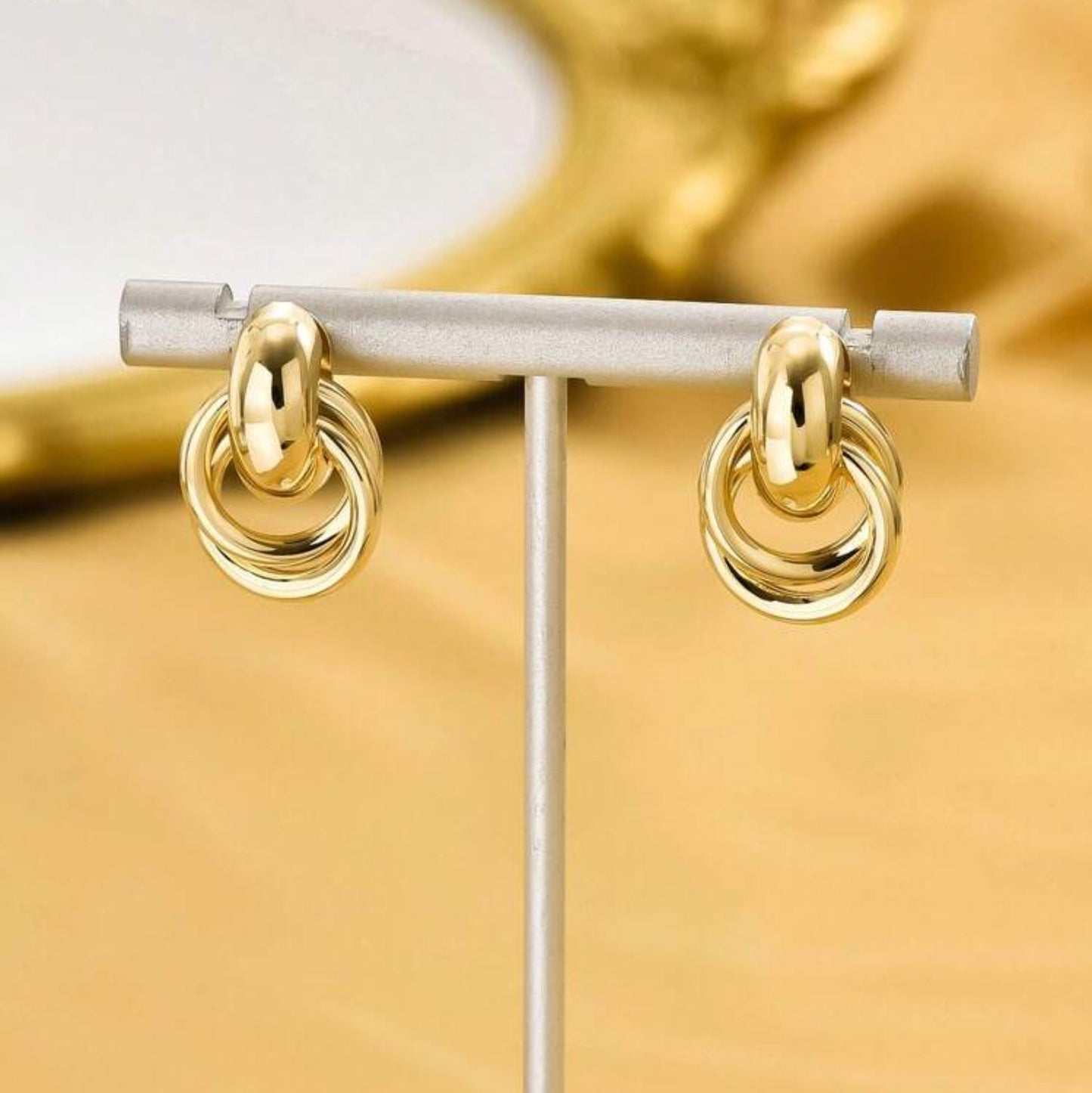 Gold circle knot earrings on a display