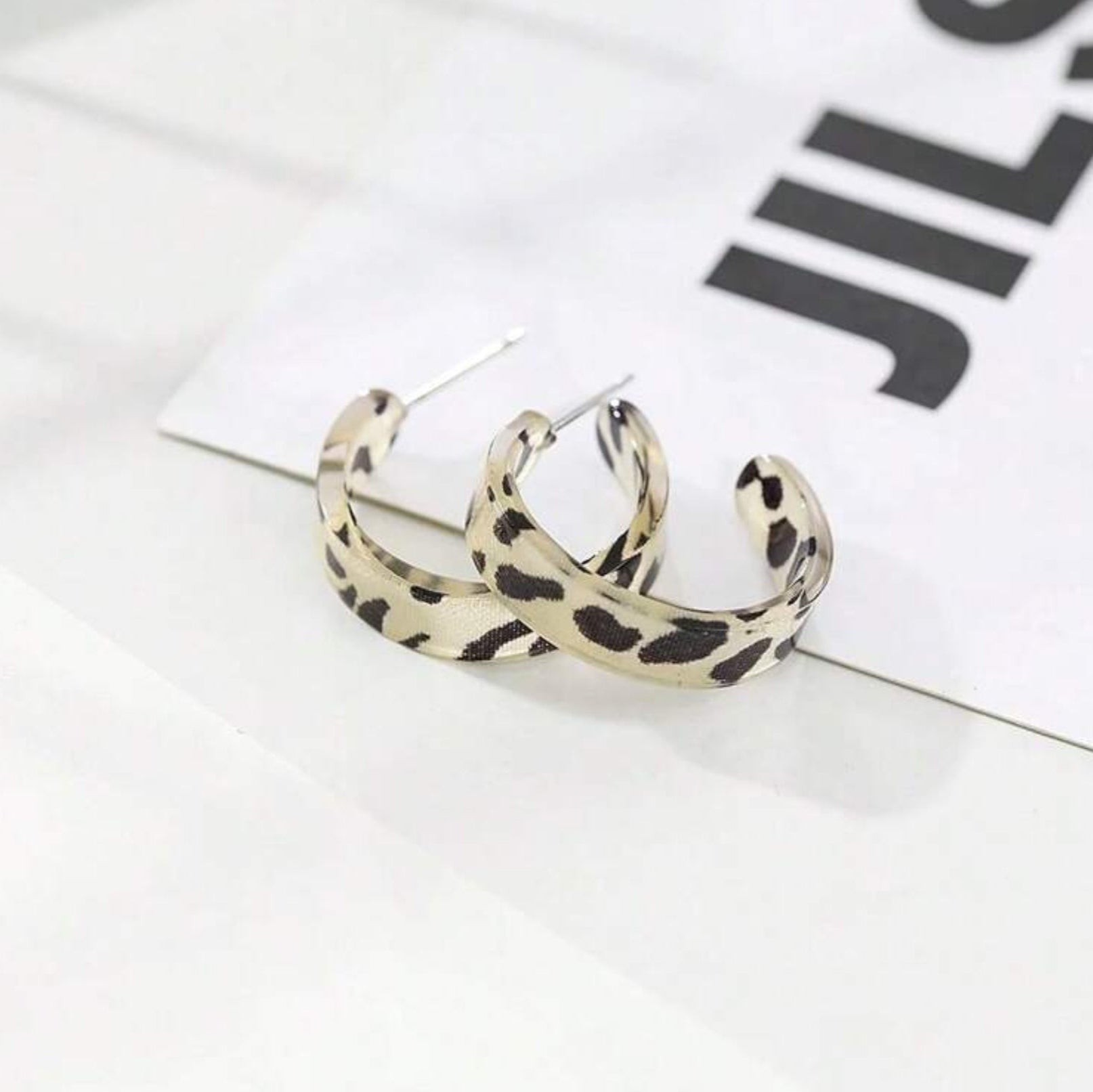 Leopard print hoop earrings on a white surface with a blurred background