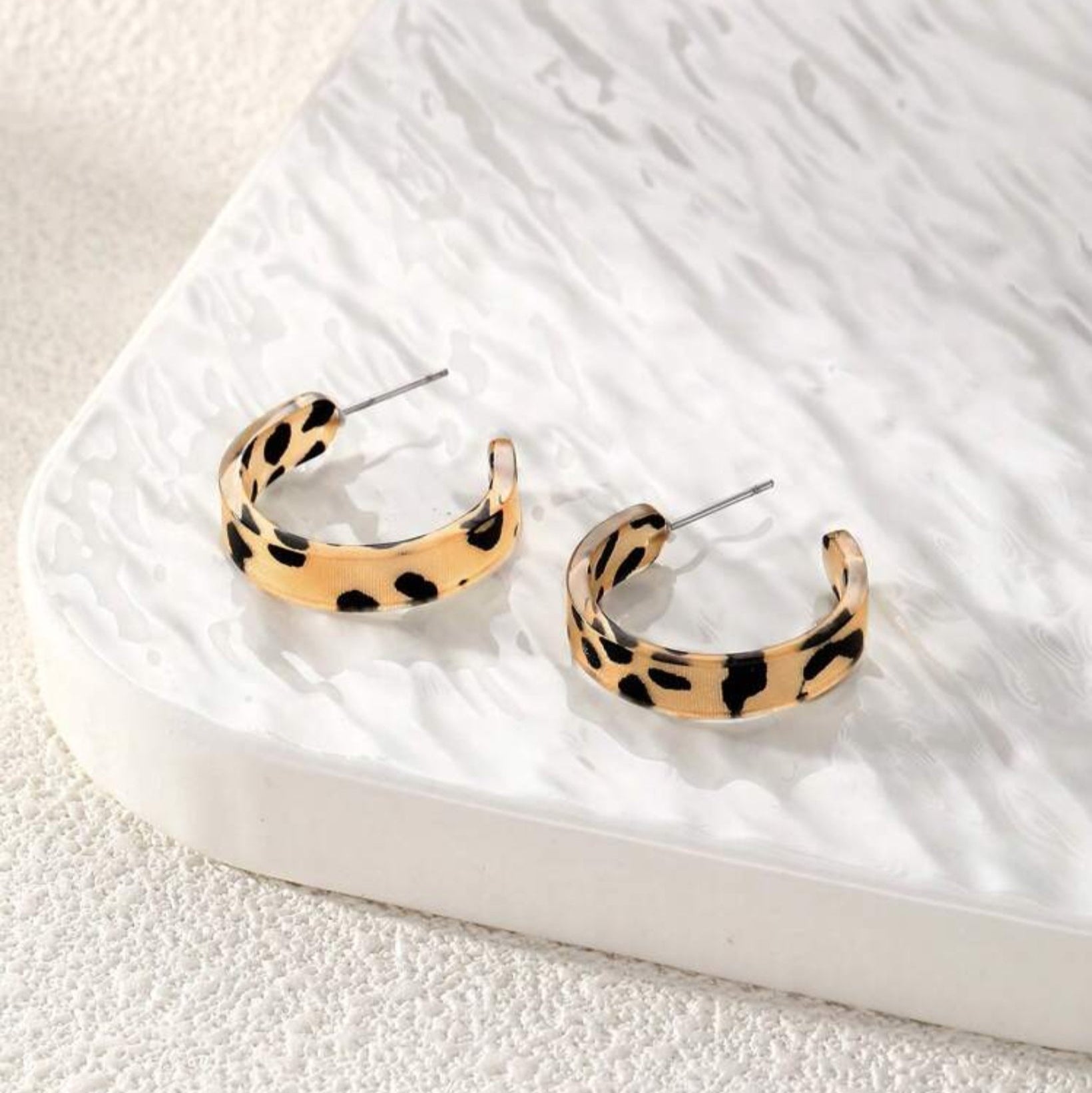 Leopard print hoop earrings on a marble surface