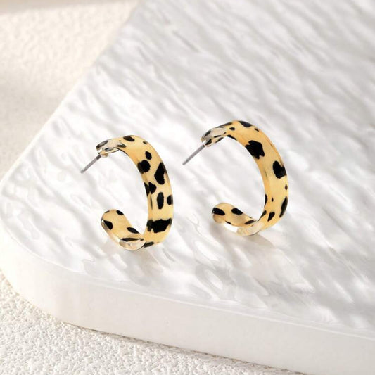 Leopard print hoop earrings on a textured white surface