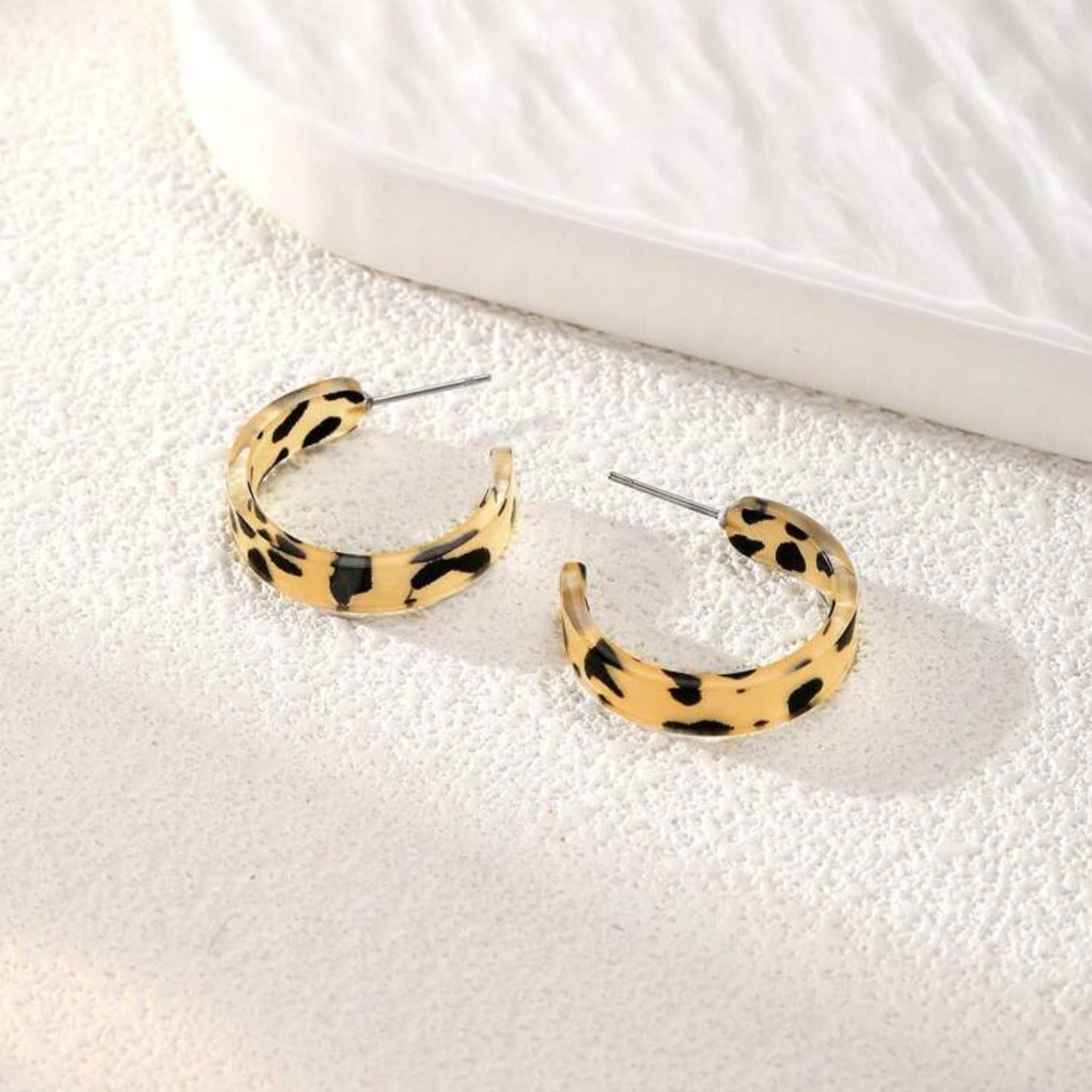 Leopard print hoop earrings on a textured white surface