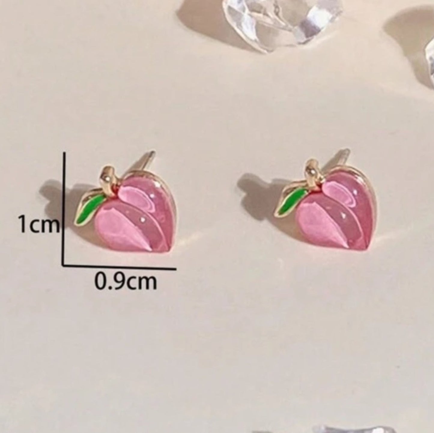 Pink peach-shaped earrings with green leaves on a white background, accompanied by measurement details.