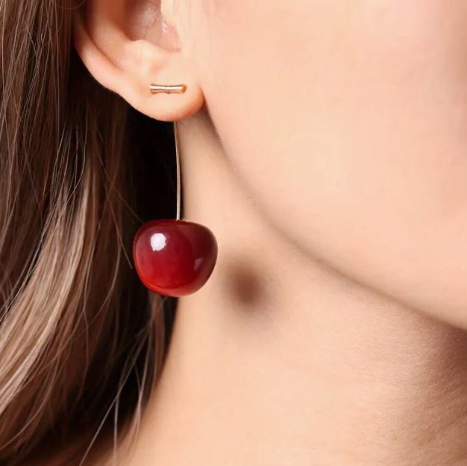 Close-up of a person wearing a red cherry-shaped earring.
