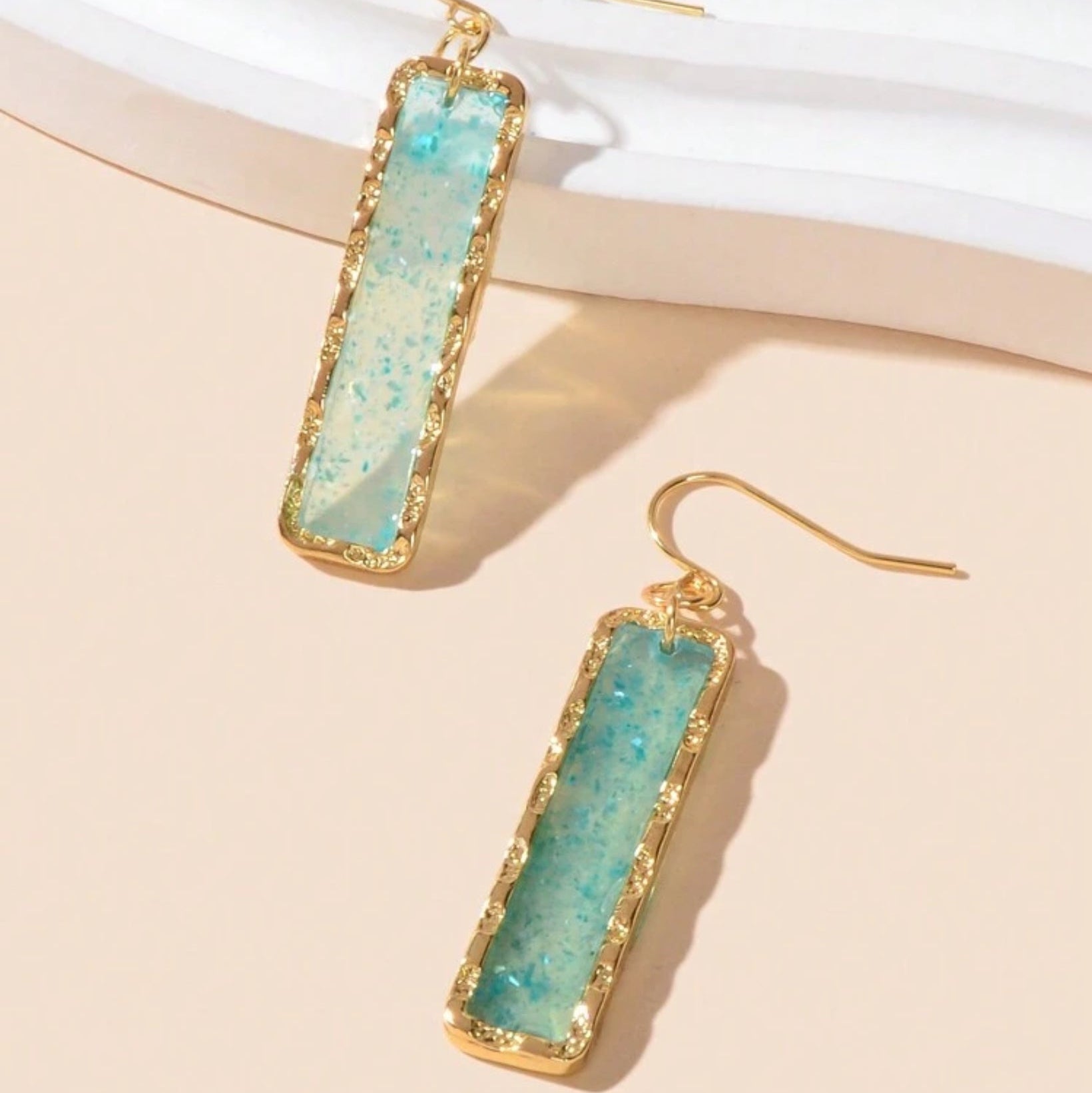 Ocean Mist Sea Glass Earrings with turquoise stone and gold frame on a beige background