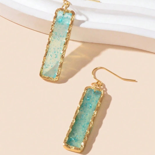 Ocean Mist Sea Glass Earrings with turquoise stone and gold frame on a beige background