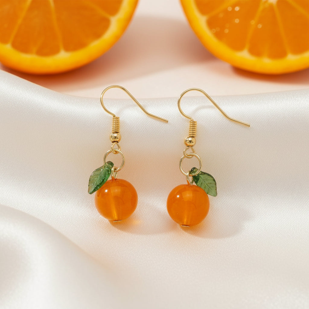Orange fruit-shaped earrings with gold hooks on a beige background