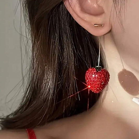 Close-up of a person wearing a red heart-shaped earring with a sparkly effect.