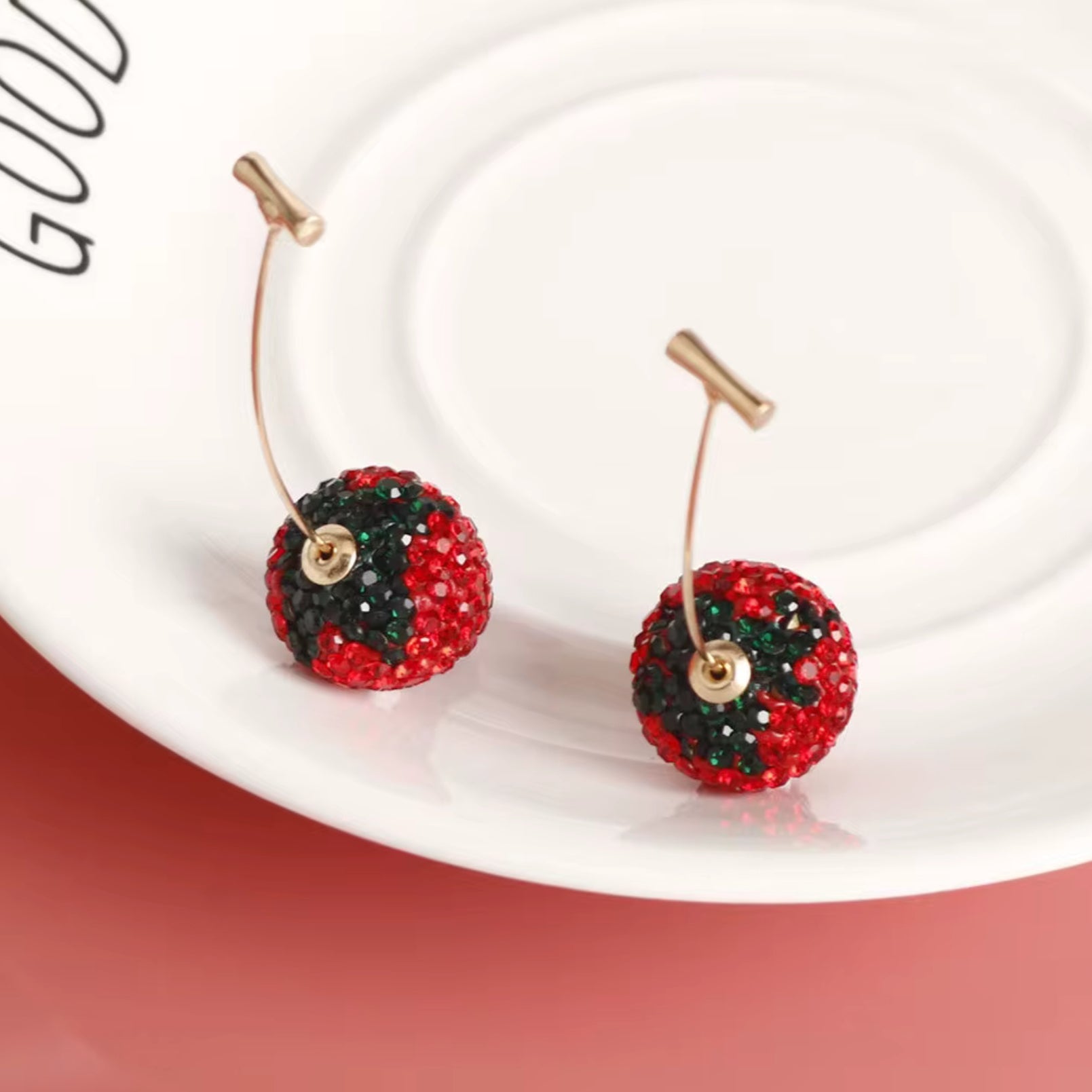 Red and green beaded earrings on a white plate with 'GOOD' visible