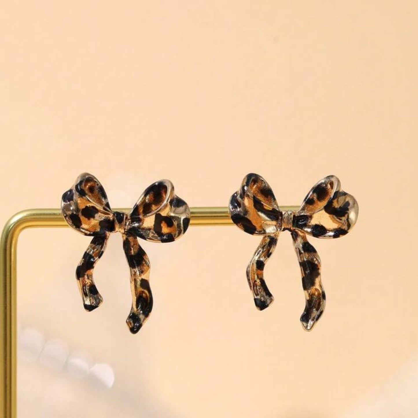 Leopard print bow earrings on a beige background