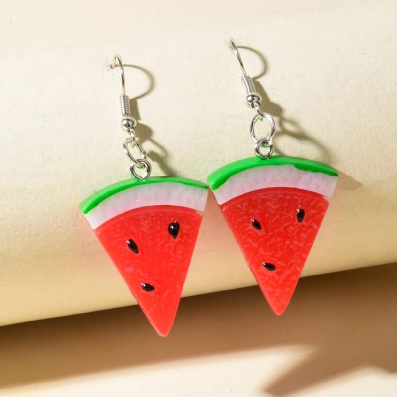 Watermelon slice earrings on a beige background