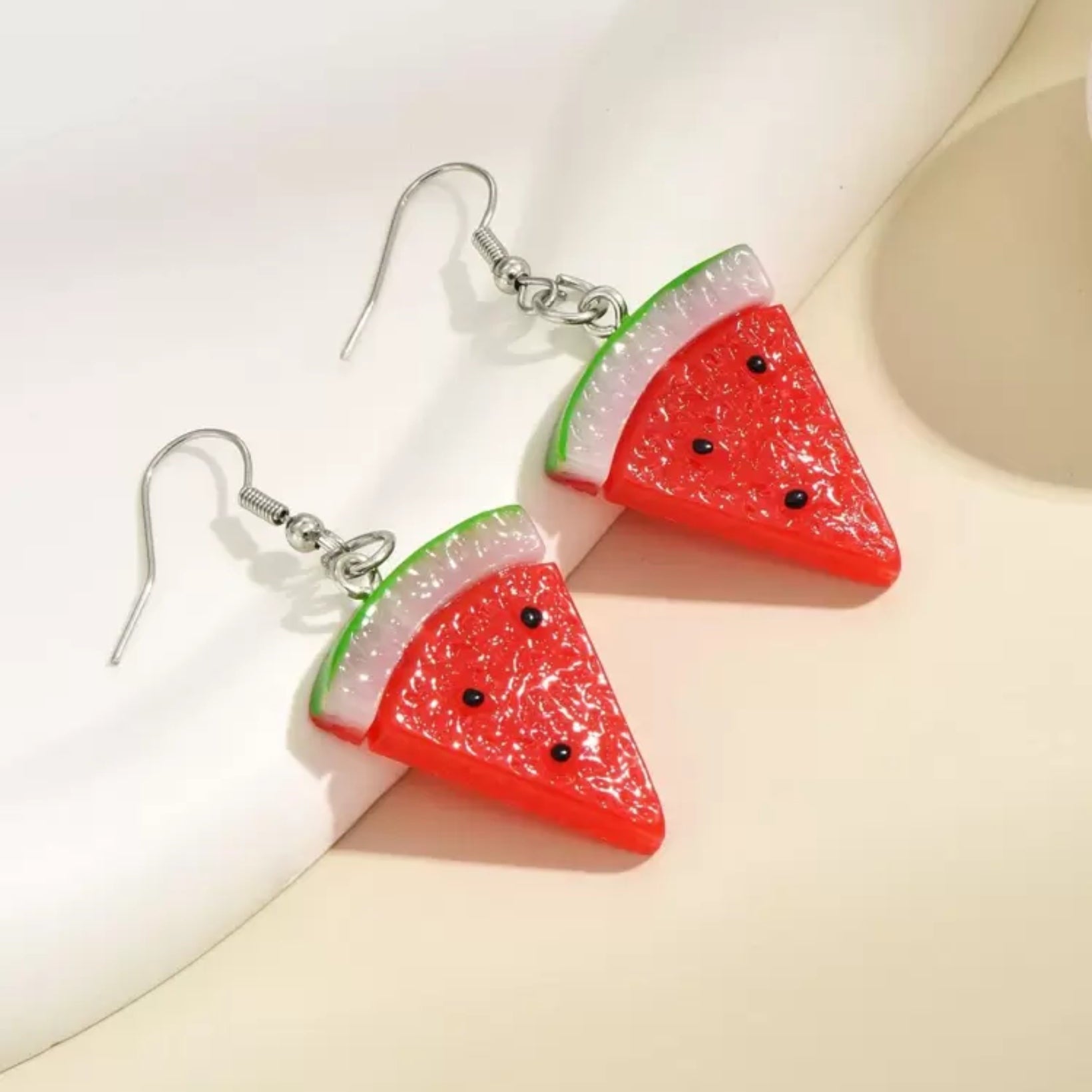 Watermelon slice earrings on a light background