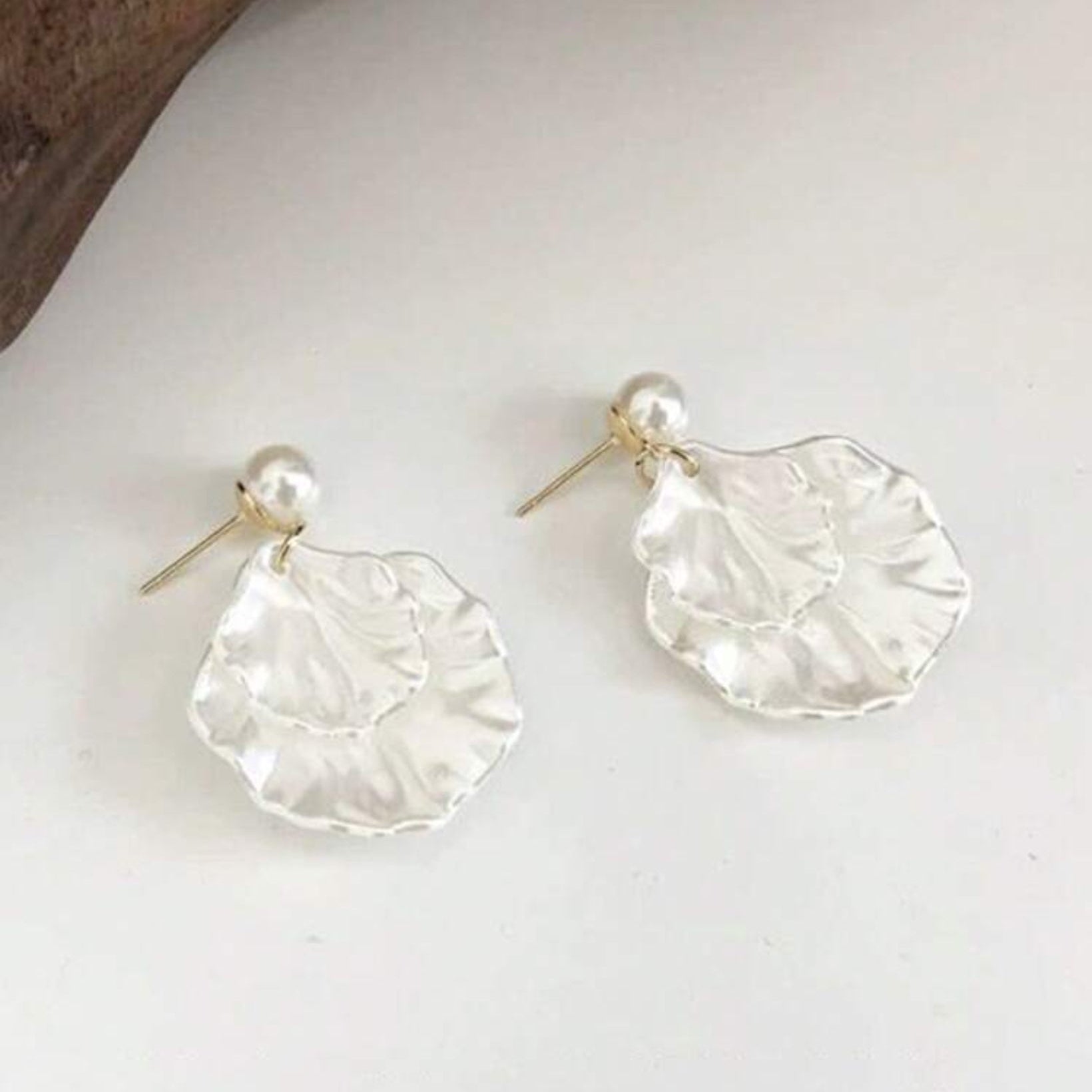 Pair of silver earrings with a pearl accent on a white surface