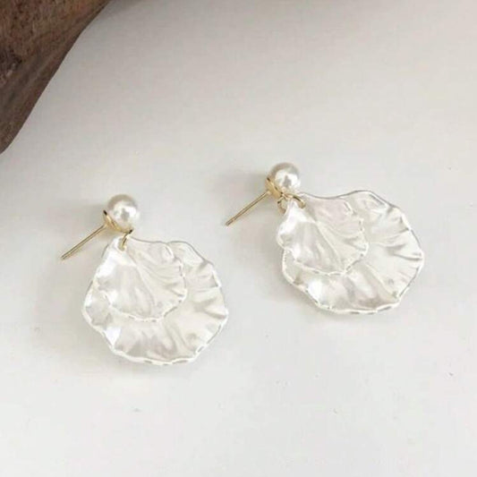 Pair of silver earrings with a pearl accent on a white surface