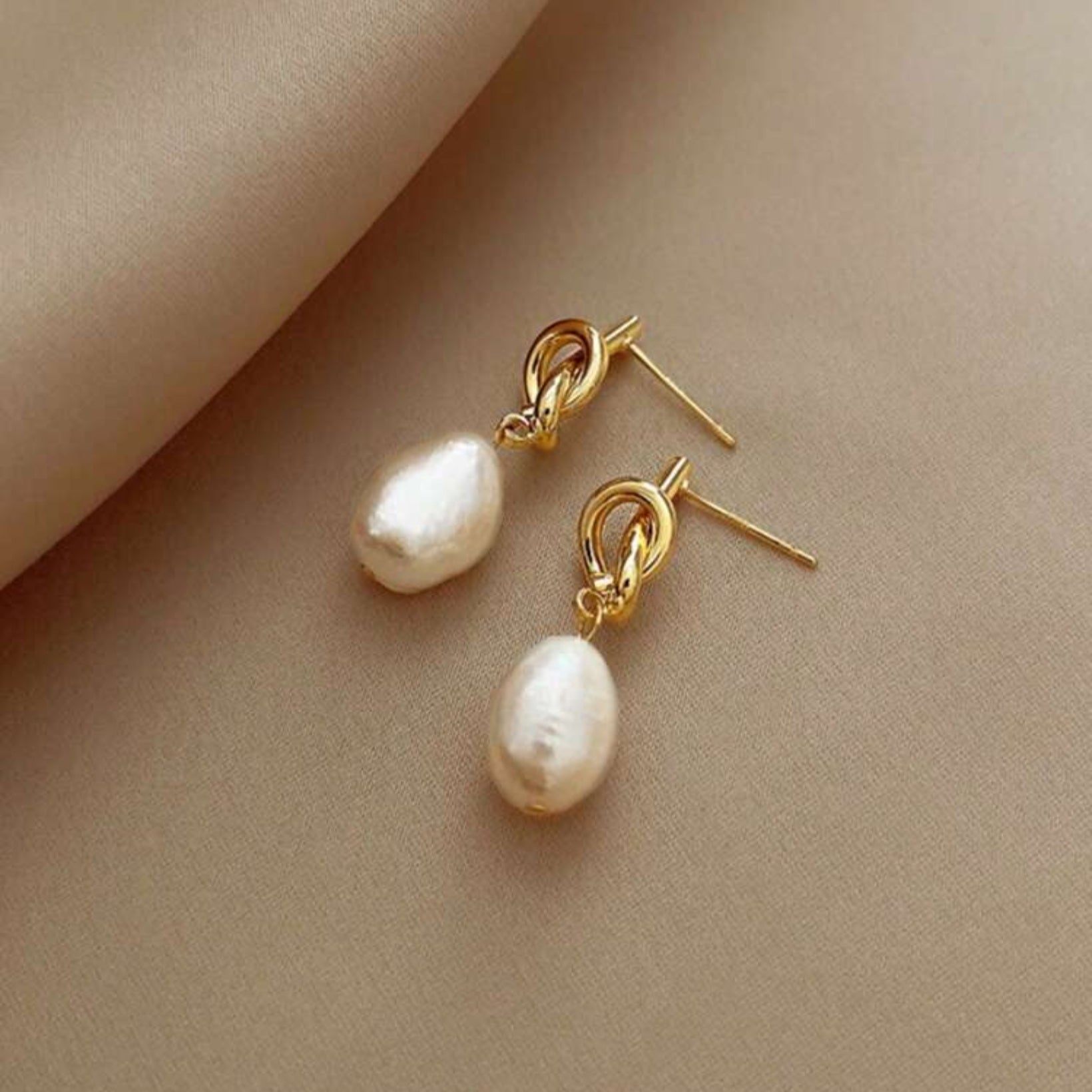 Gold knot drop earrings with classic pearl accents, elegant dangle style