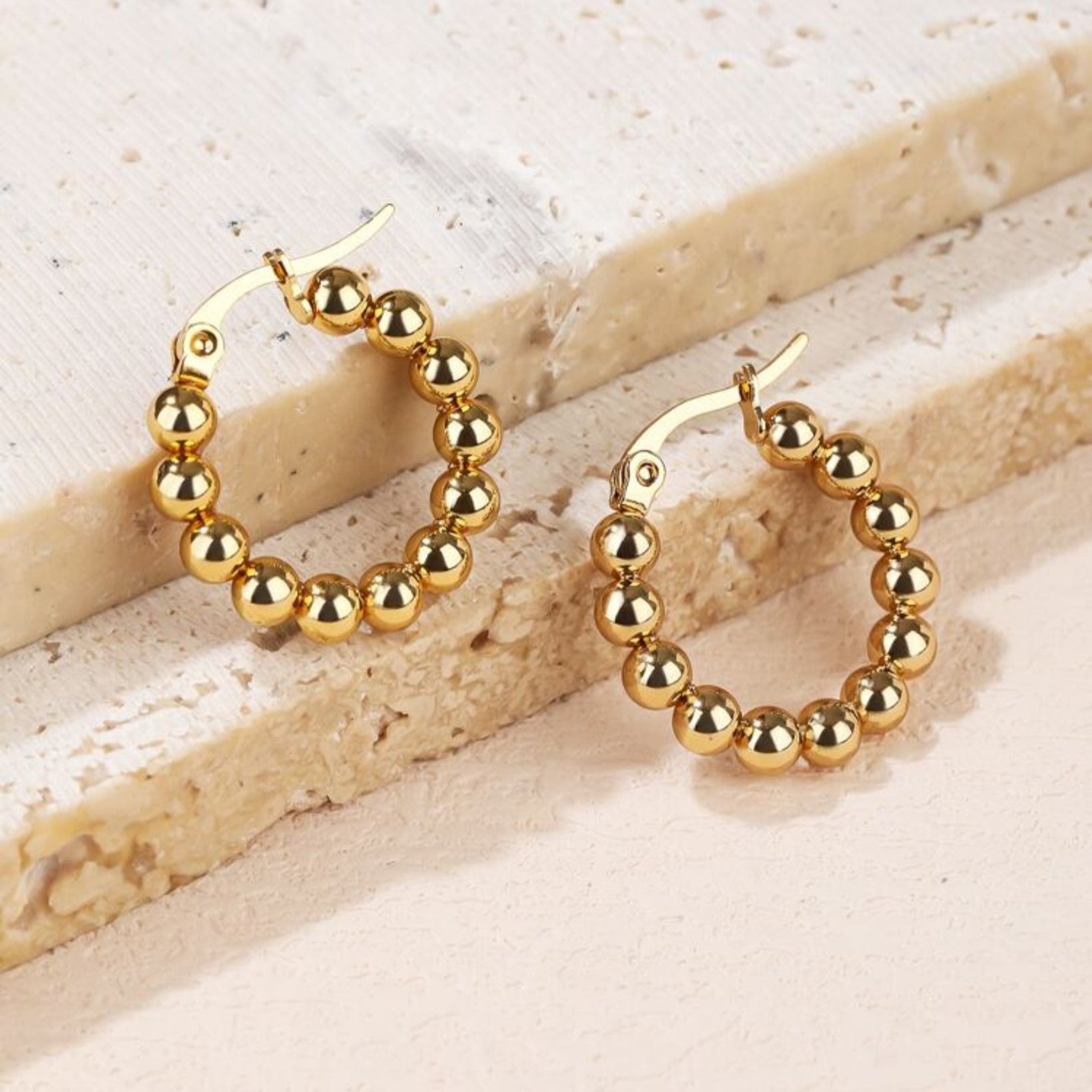 Gold hoop earrings with beaded design on a light background