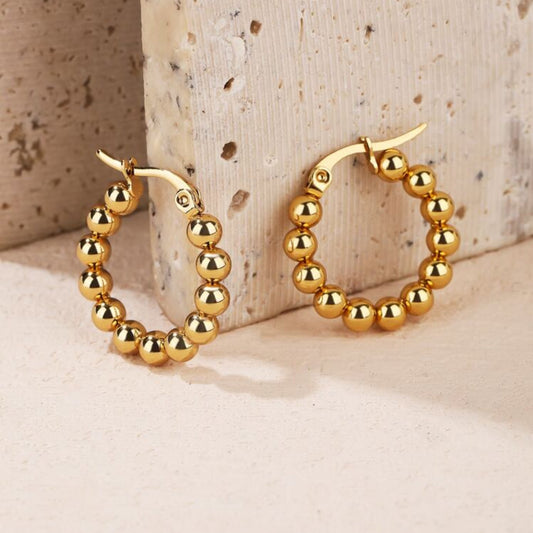 Gold hoop earrings featuring smooth rounded beads along the hoop