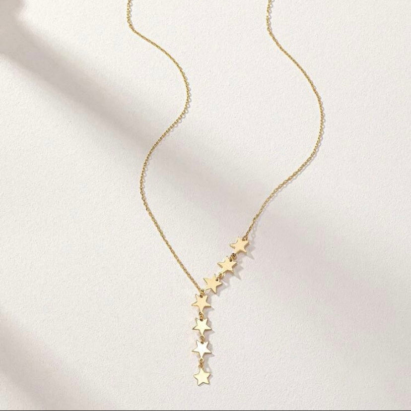 Gold star necklace on a light pink background