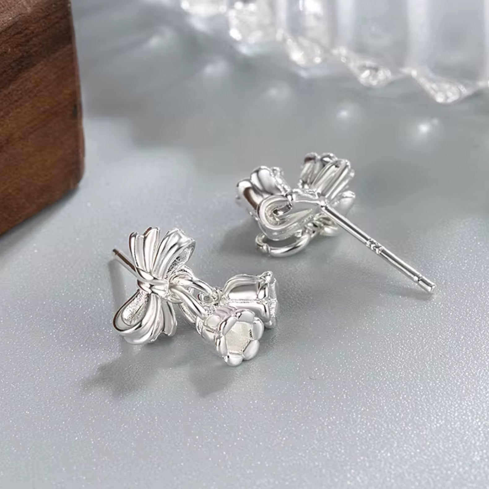 Silver bow-shaped earrings on a light gray surface