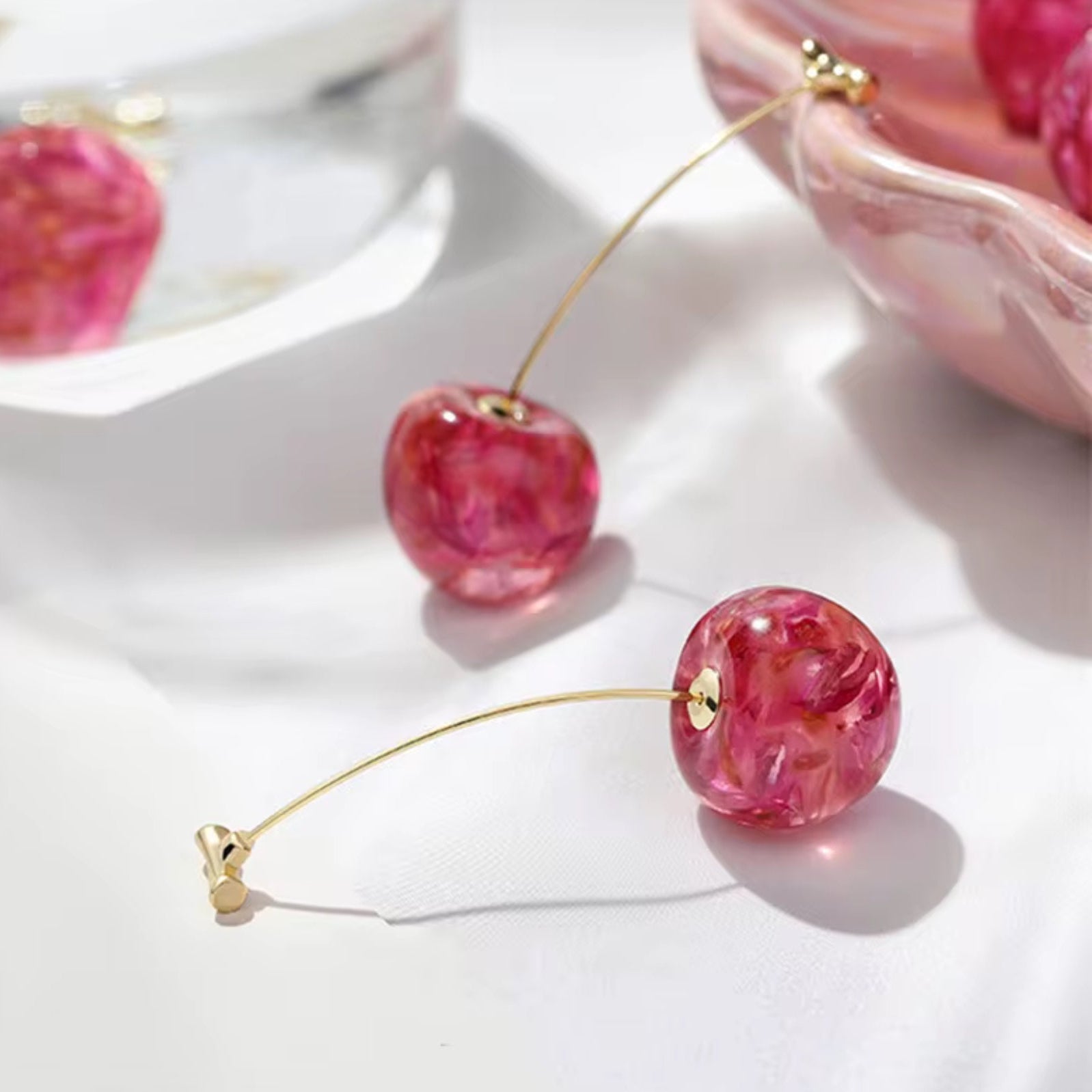 Gold stud earrings shaped like pink cherries with glossy finish