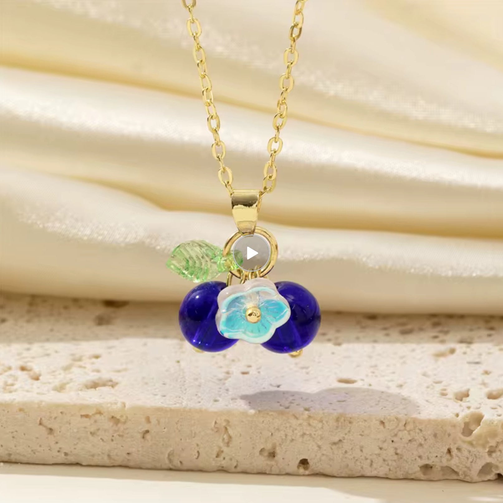 Necklace with a blue floral pendant on a beige stone background