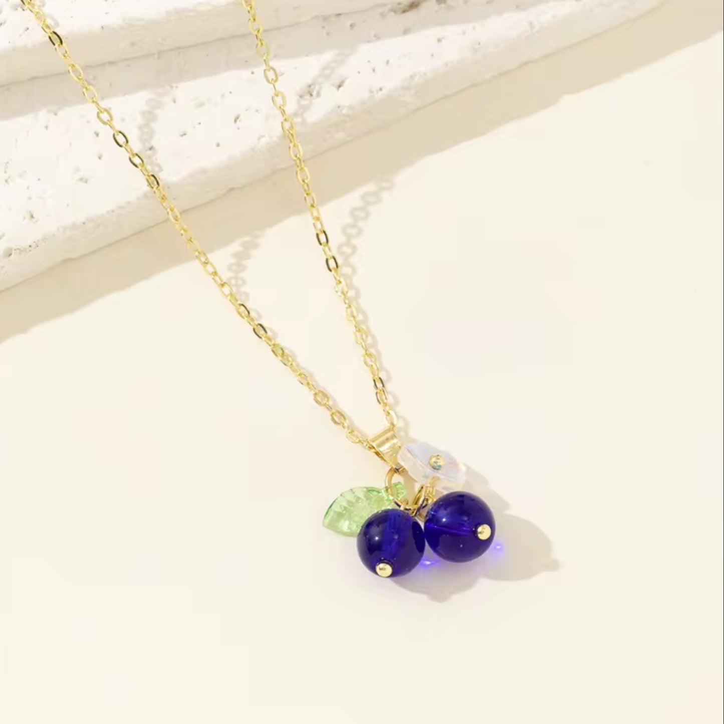 Necklace with purple beads and a green leaf charm on a light background