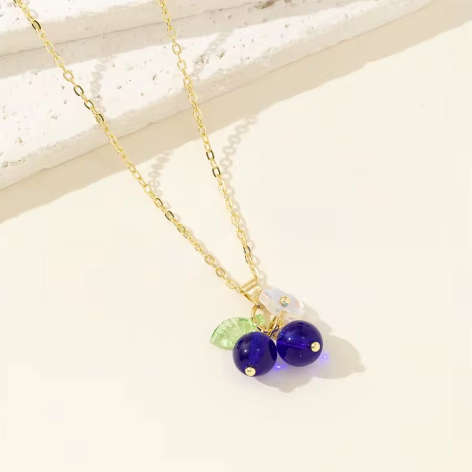 Necklace with purple beads and a green leaf charm on a light background