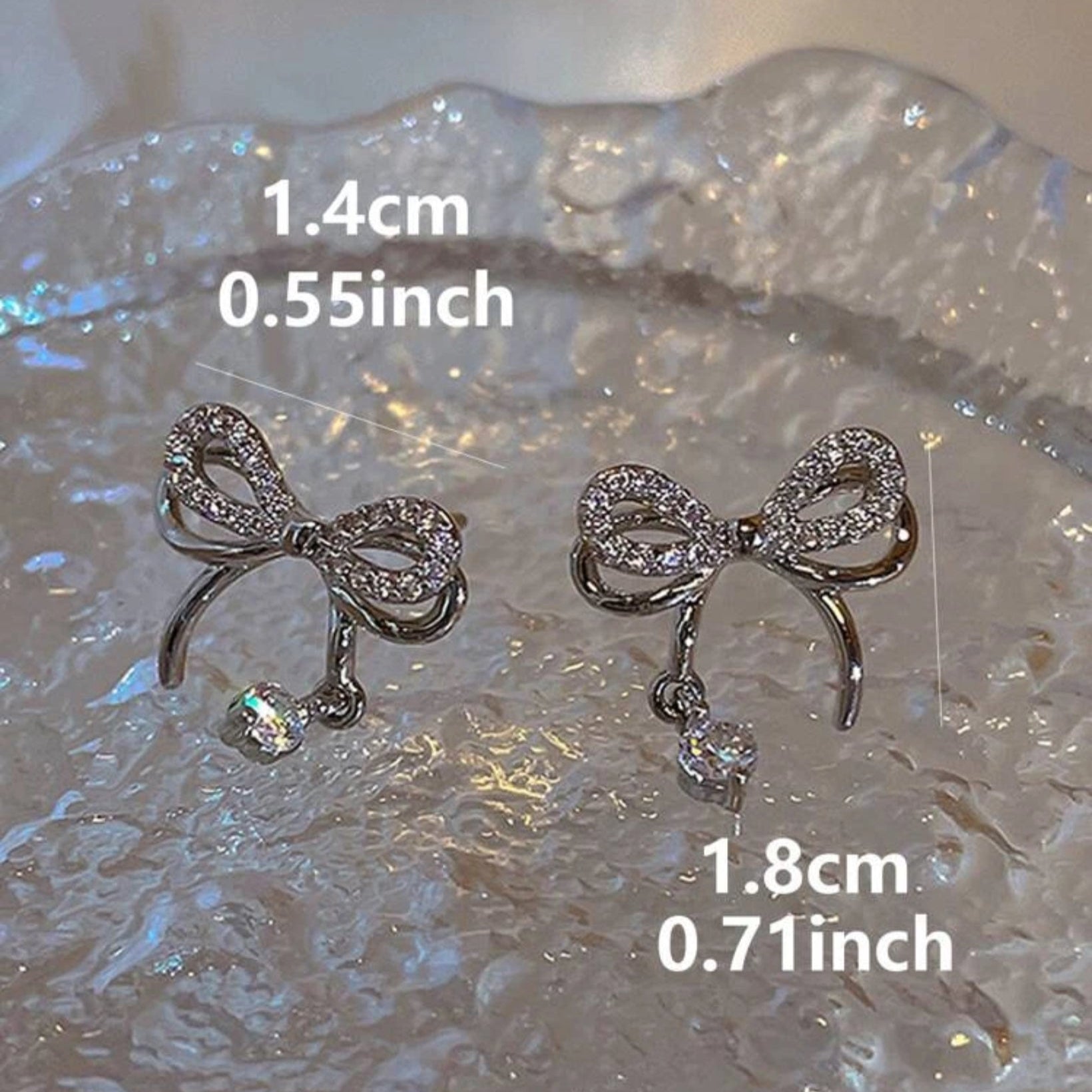 Bow-shaped earrings with measurements on a textured surface