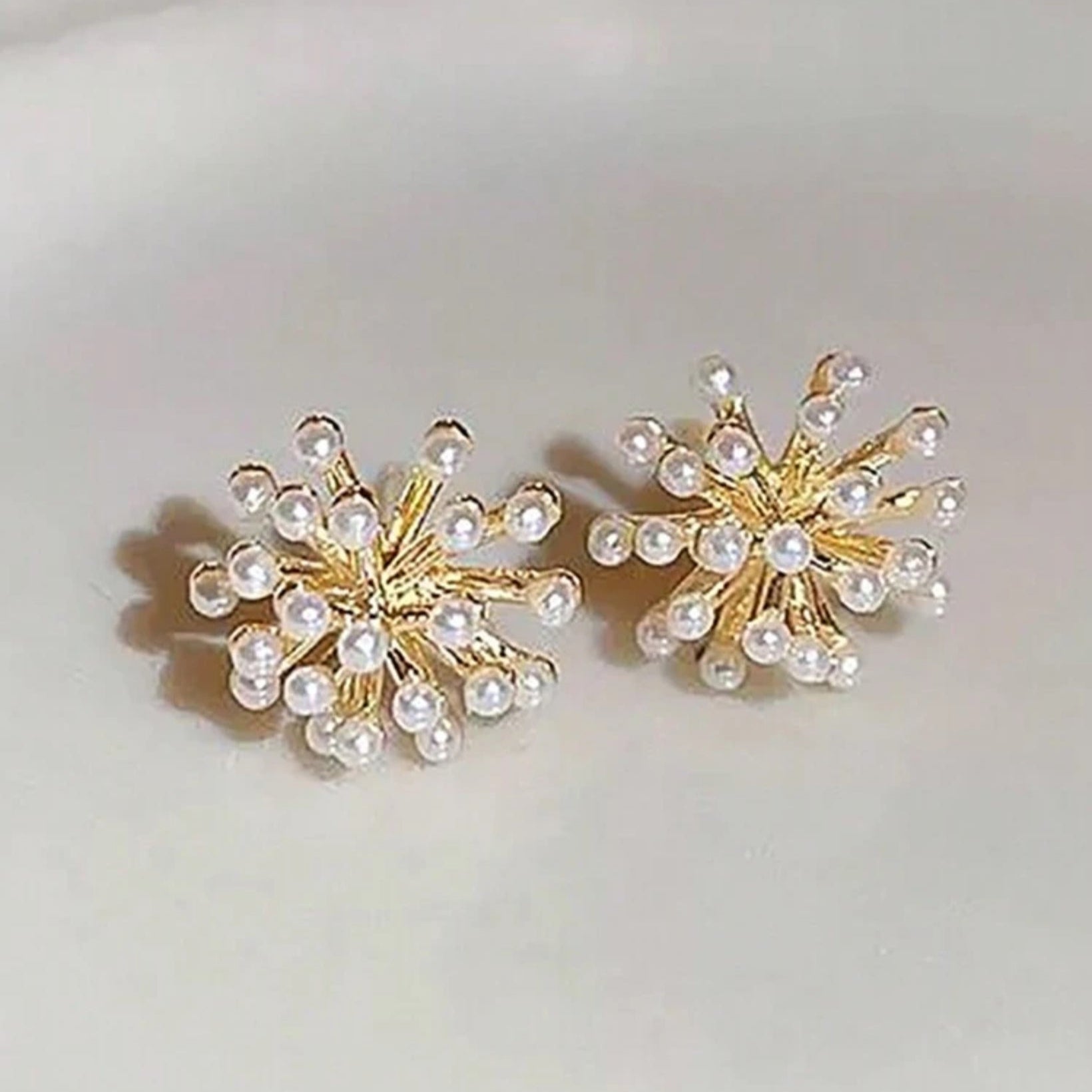 Gold stud earrings with clustered pearls in a radiant burst design