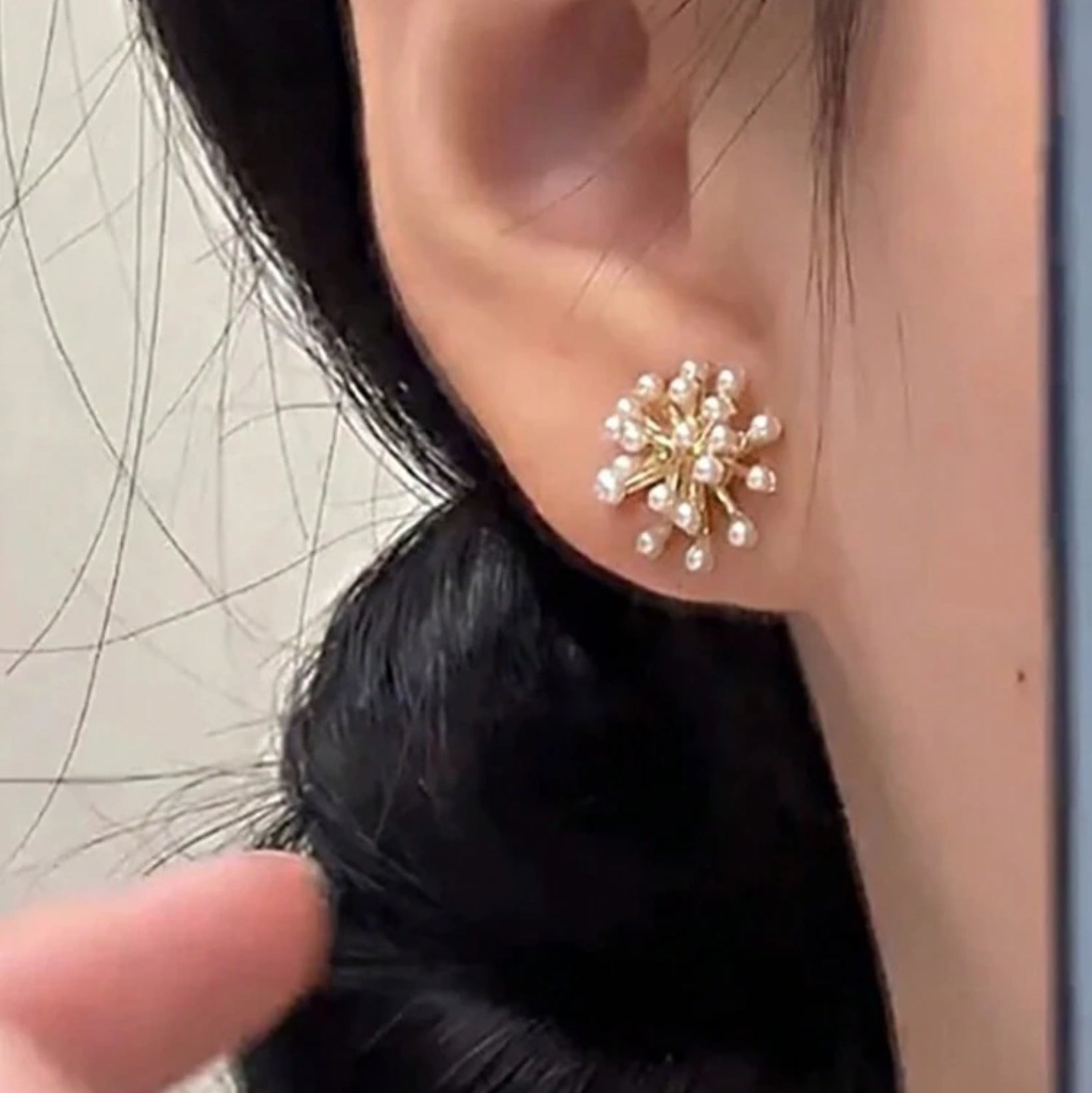 Close-up of a person wearing a gold and pearl earring.