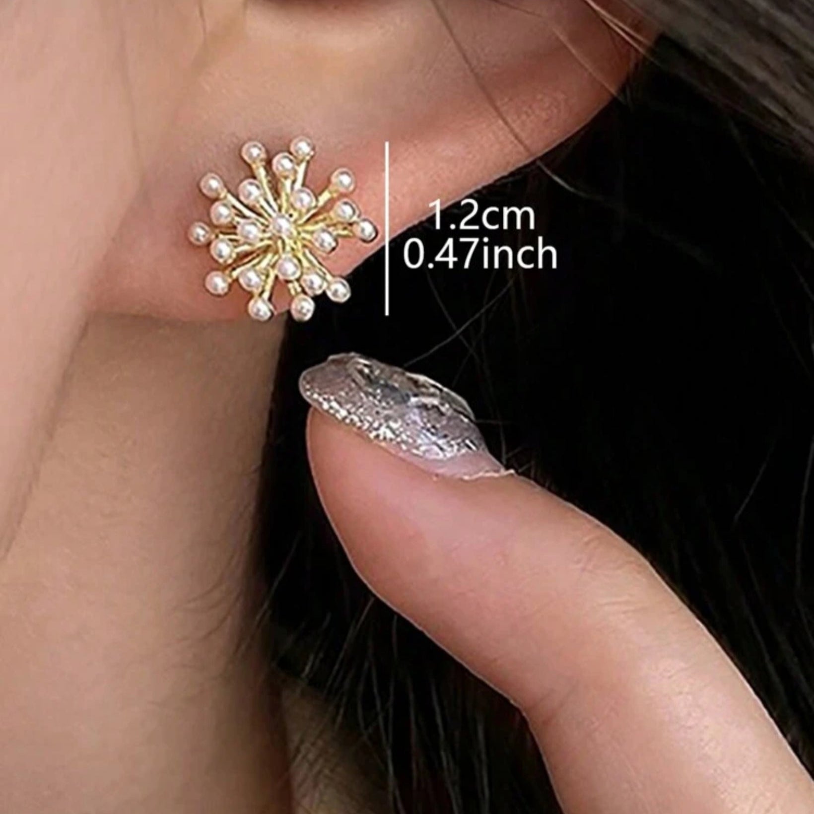 Gold and silver earrings being held by a finger with measurements displayed.