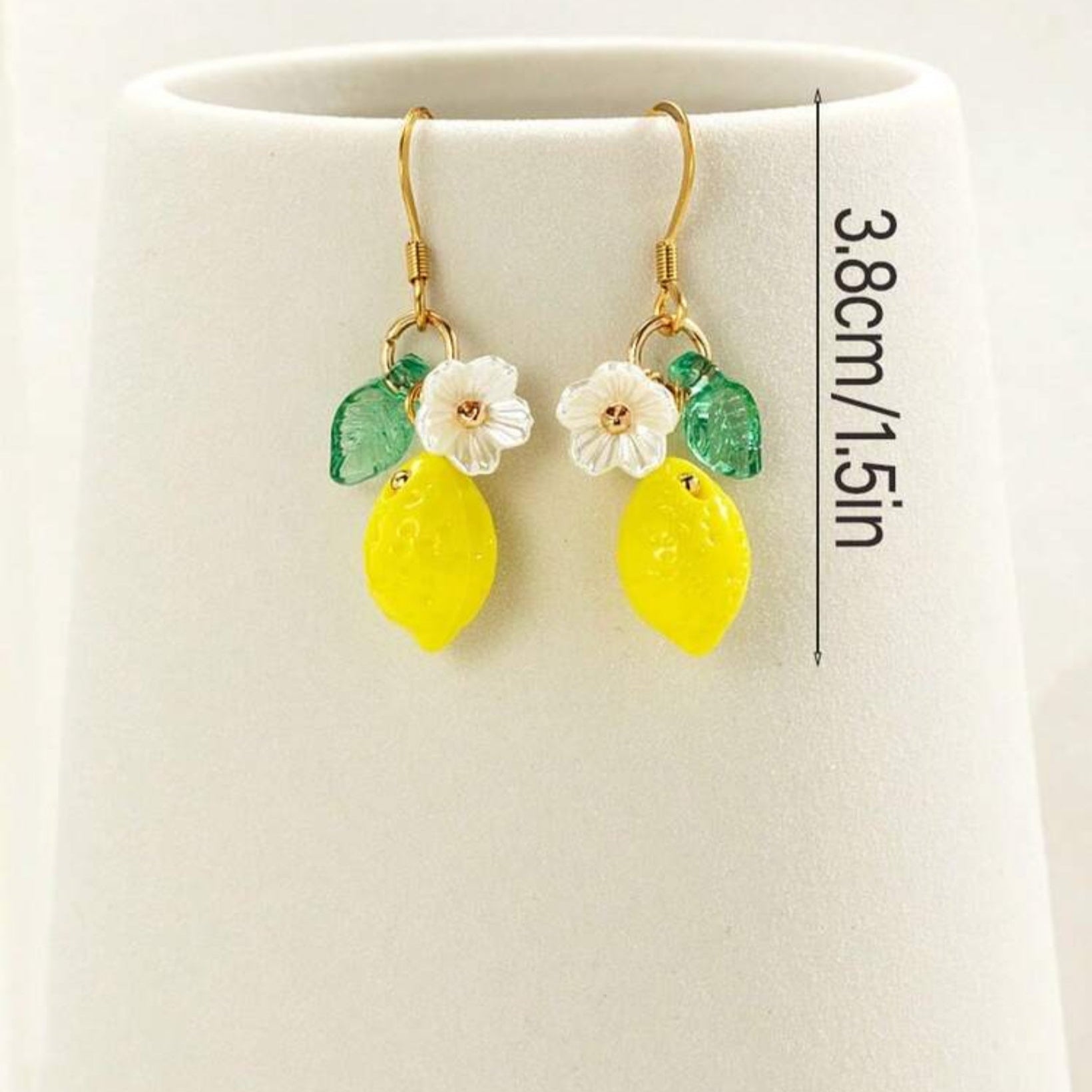 Pair of earrings with lemon and flower designs on a white background