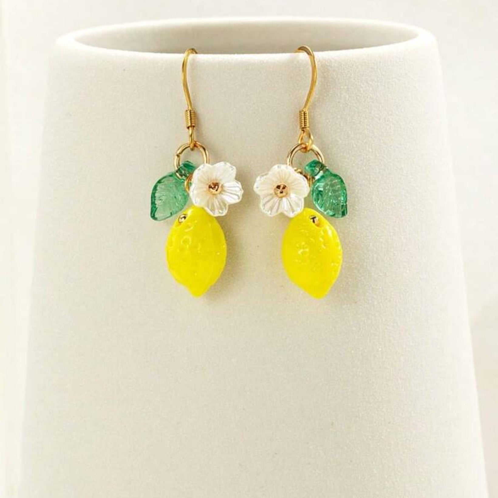 Pair of earrings with lemon and flower designs on a white background