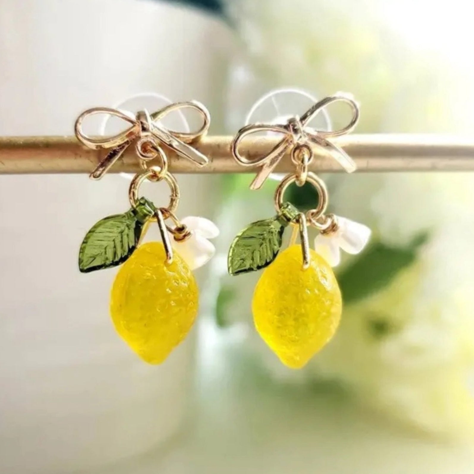 Gold bow stud earrings with dangling lemon accents