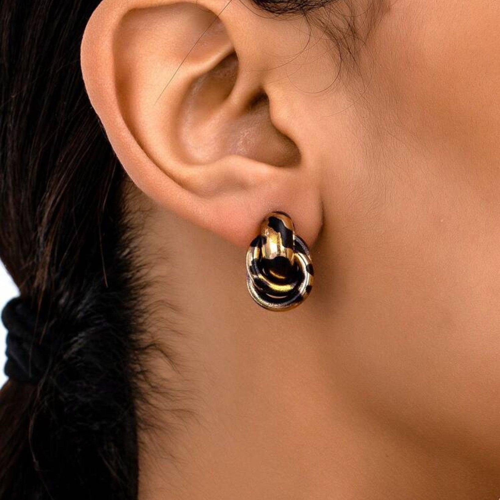Close-up of an ear wearing a Leopard Circle Knot Earring with a blurred background
