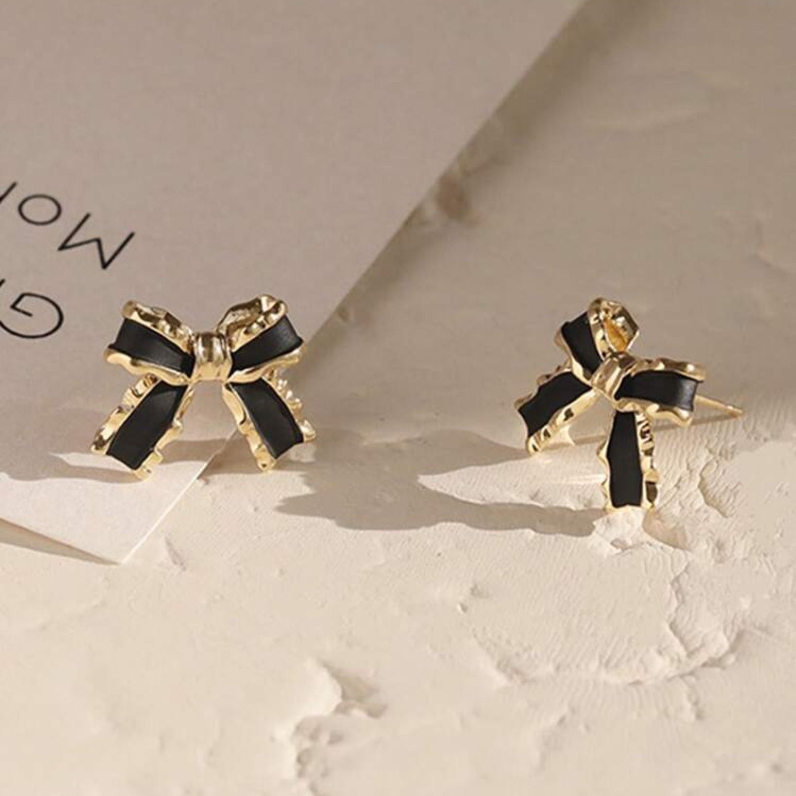 Black & Gold Bow Earrings with black centers on a light background