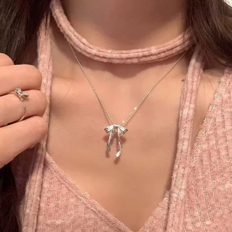 Silver Ribbon Bow Necklace on a person wearing a pink top.